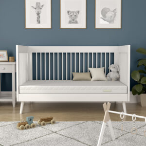 Modern nursery with cot containing a white mattress and stuffed toys