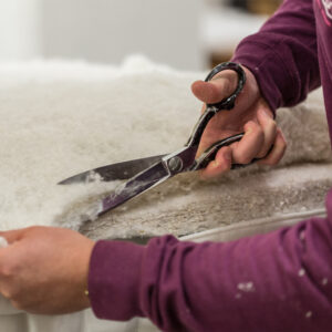 Close-up of hands cutting fabric using a pair of scissors.